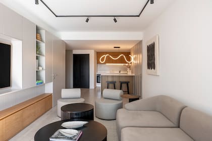 Las mesas ratonas permiten guardar textiles y el mueble del estar se diseñó para ocultar cables, mandos y cargadores (todo de Ideï).