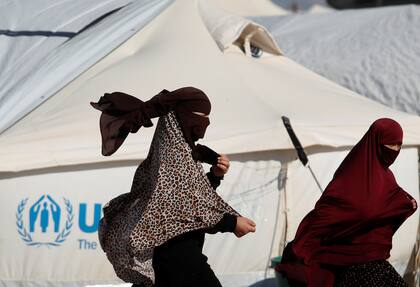 Las mujeres pasan junto a una carpa en el campamento de al-Hol