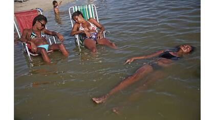 Las mujeres se relajan en el estanque artificial conocido como piscinao, o piscina grande, en los suburbios del norte de Río de Janeiro, Brasil.