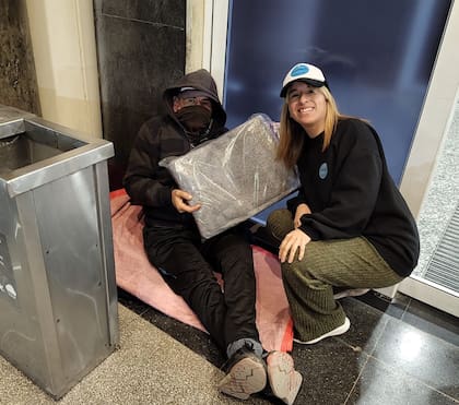 Las organizaciones brindan diferentes tipos de asistencia; en la imagen, una voluntaria de la asociación civil Puente le acerca una manta a una de las personas que pasa las noches en Aeroparque