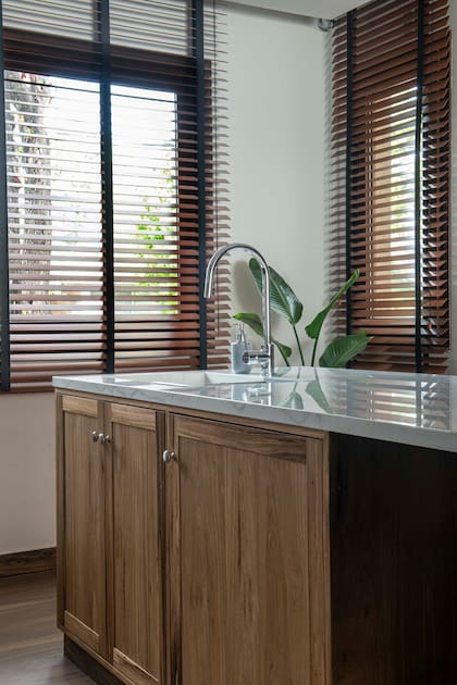 Las persianas americanas de madera regulan la luz, dan privacidad sobre todo a la noche, cuando la casa se ve más desde la calle, y una perfecta armonía con el piso y las puertas de la isla.