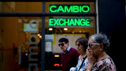 Las personas caminan frente a una casa de cambio en Buenos Aires, Argentina (AP Foto/Natacha Pisarenko)