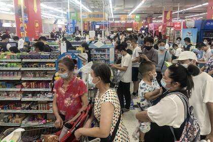 Las personas comprando artículos en un supermercado en Wuhan ya que las autoridades dijeron que impondrán restricciones para analizar a toda su población para detectar Covid-19