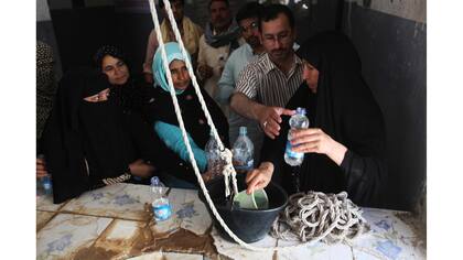 Las personas hacen cola para recoger el agua bendita en el interior del santuario del imán Mahdi en el cementerio de Wadi al-Salam