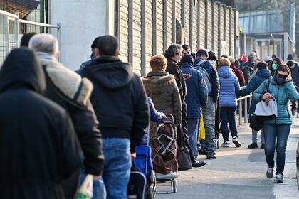 Las personas necesitadas reciben una bolsa con comida gratis en la asociación laica italiana, no partidista y sin fines de lucro llamada "Pane Quotidiano" (Pan de cada día) en Milán, el 8 de marzo de 2021