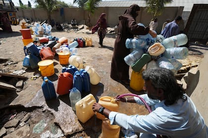 Las personas obtienen agua potable de un punto de recolección de agua en un barrio marginal, en Karachi, Pakistán
