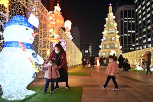 Las personas posan para las fotos mientras visitan una exhibicin de luces navideas en el centro de Sel, el 23 de diciembre de 2021