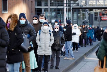 Las personas que llevan máscaras faciales hacen una cola de 700 metros para vacunarse en la Filarmónica del Elba 
en la ciudad de Hamburgo, en el norte de Alemania, el 22 de noviembre de 2021, ya que se ha abierto un centro de vacunación en medio de una oleada de infecciones durante la pandemia de coronavirus (Covid-19) en curso