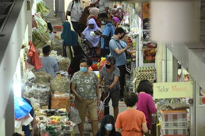 Las personas, que usan barbijos como medida preventiva contra la propagación del nuevo coronavirus, compran alimentos en el mercado Geylang Serai en Singapur el 8 de abril de 2020