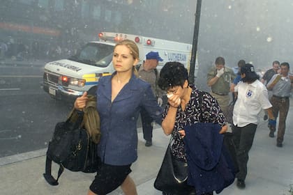 Las personas se cubren la cara de la lluvia de polvo y escombros cuando abandonan el área del ataque al World Trade Center