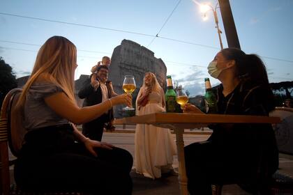 Las personas se reúnen para tomar un aperitivo frente a un bar junto al Coliseo en Roma, el 18 de mayo de 2020
