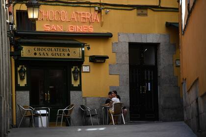 Las personas se sientan en la chocolatería San Ginés en Madrid el 25 de mayo de 2020, luego de que las medidas de bloqueo del coronavirus finalmente se flexibilizaron para las personas en Madrid y Barcelona
