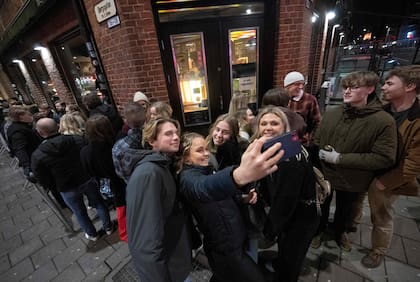 Las personas se toman fotos mientras hacen cola afuera del club nocturno KB en Malmoe, Suecia