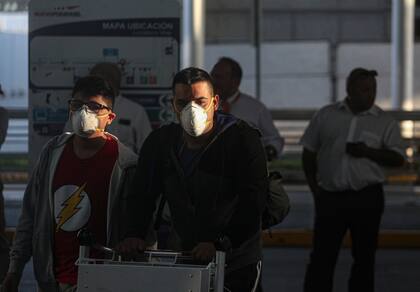 Las personas utilizan barbijos en el Aeropuerto Internacional Comodoro Arturo Merino Benítez en Santiago de Chile