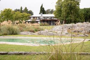 Las piedras y los escalones curvos de granito también definen las terrazas que contienen a la pileta curva propuesta por Brookes. Todo esto incluye a la casona y a la pileta como parte de la postal.