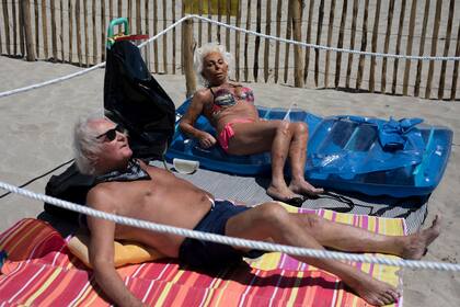 Una pareja toma sol en un playa de Niza dentro de un cerco marcado con sogas para mantener el distanciamiento social