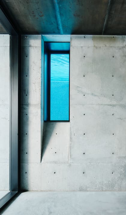Las rajas verticales en la pared de hormigón se repiten en diferentes sectores y con distinta intencionalidad: un desprendimiento del material que hace de escalón para la pileta, una ventana que permite ver el agua o una chimenea.