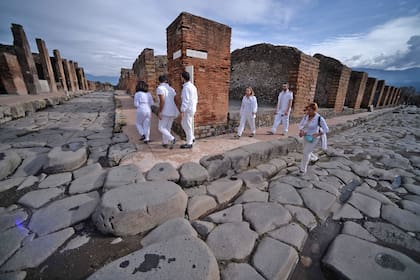 Los visitantes caminan por la adoquinada Vía del Vesubio. Tras la erupción del Volcán en el año 79 d.C., la ciudad quedó cubierta por un espeso extracto de piedras y cenizas volcánicas