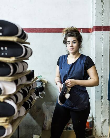 Las trabajadoras quitan las rebarbas del PVC de cada una de las suelas y pegan las plantillas.