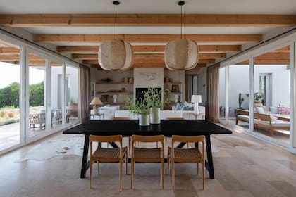 Las vigas, decidieron dejarlas sin cepillar, bien rústicas. “Las vimos así, crudas, y entendimos que todo tenía sentido si las dejábamos al natural”, cuentan. Lámparas (Talleres Sustentables). Sillas (Harturo). Mesa (Wood Market). Cortinas (Gloria Furtado).