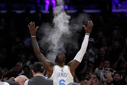 LeBron James arroja polvo al aire antes del inicio del partido de la NBA que enfrentó a su equipo, los Lakers de Los Ángeles, y a los Warriors de Golden State, el 23 de febrero de 2023, en Los Ángeles. (AP Foto/Mark J. Terrill)