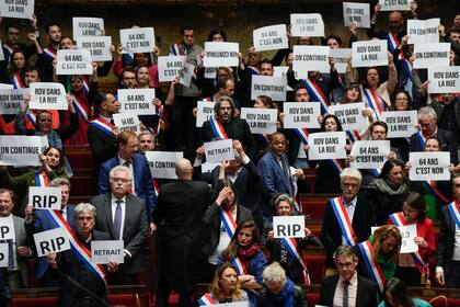 Legisladores de extrema izquierda muestran su descontento durante la sesión de la Asamblea Nacional, en París, el lunes 20 de marzo de 2023. 