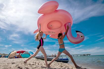 Lena y Jara, de diez años, llevan un flamenco inflado en la playa de Rerik en el Mar Báltico, noreste de Alemania
