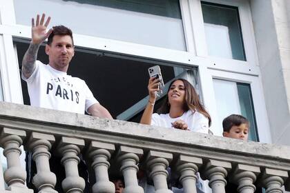Leo, Anto y Thiago saludan a los fans desde una de las suites presidenciales del hotel. Ella captura el momento con su teléfono.