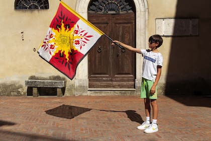 Leonardo juega con la bandera de Pienza en un callejón del pueblo.