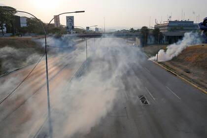 El gas lacrimógeno cubre una carretera vacía junto a la base aérea La Carlota en Caracas