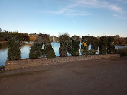 Letras que nombran a la ciudad con el Lago del Fuerte detrás