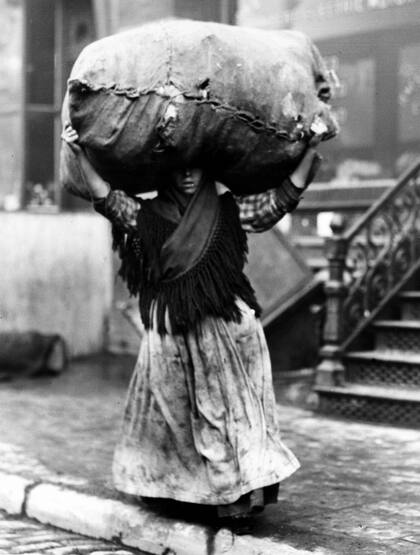 Una mujer migrante en las calles de Nueva York, con un bulto de ropa en la cabeza