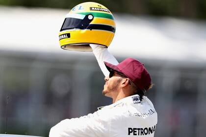 Lewis Hamilton y un casco conmemorativo de Ayrton Senna, luego de batir el récord de 65 pole positions en el circuito de Silverstone; el paulista logró su primer triunfo en la Fórmula 1 en Portugal, en 1985, país en donde el británico impuso una nueva marca de triunfos