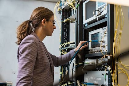 Lídia Galdino, investigadora del University College London, junto a la infraestructura utilizada para probar los algoritmos que buscan asegurar la eficiencia en la transmisión de datos por fibra óptica