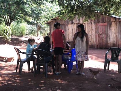 Lilian y sus hermanos hacen la tarea a la sombra de un árbol en el patio de su casa