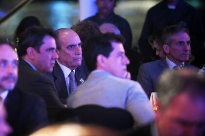 Lisandro Catalán sentado entre Guillermo Francos y Eduardo de Pedro, en la cena a beneficio del fondo de becas de la Universidad Austral, el 21 de mayo de 2024