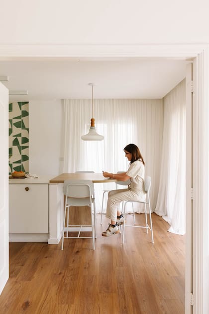 Literas, sentada en una banquetas de Estudio Te. El ingreso a la cocina es a través de una puerta doble que ya estaba en la casa y pintaron de blanco.