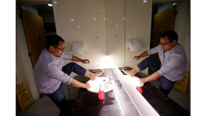 Liu Zhenyu, un administrador de clientes en Ju Mei You Pin, lava sus pies en el baño de la oficina antes de ir a dormir después de terminar el trabajo a la medianoche