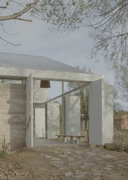 El acceso principal se ve desde la calle y da inicio a la fachada metálica que se repite en los laterales y el fondo.