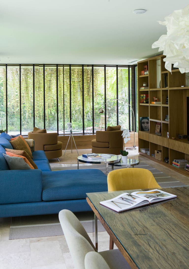 La artista Patricia Pelliccioni y su marido, el ingeniero Jorge Young. La biblioteca del living es un diseño de Patricia ejecutado por Cómodo Muebles. Alfombra (Salazar Casa). Sillón azul (CDI).