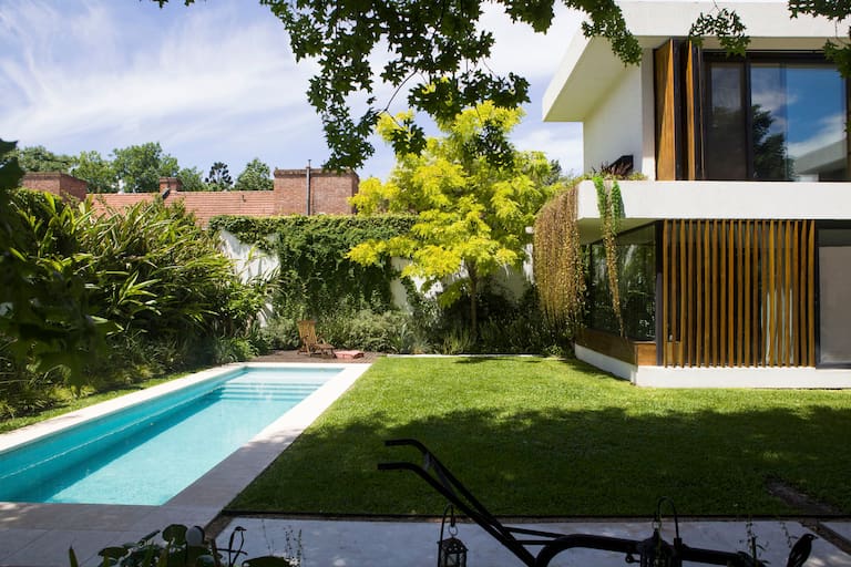 "El terreno perteneció a un matrimonio alemán y tenía una pileta enorme que luego rellenamos". Hoy se transformó en un jardín zonificado, exuberante y selvático,
tal como soñaban los dueños: luz, naturaleza y arte en perfecta armonía. Parasoles y postigones de kiri (Carpintería Fernández Rotela).
