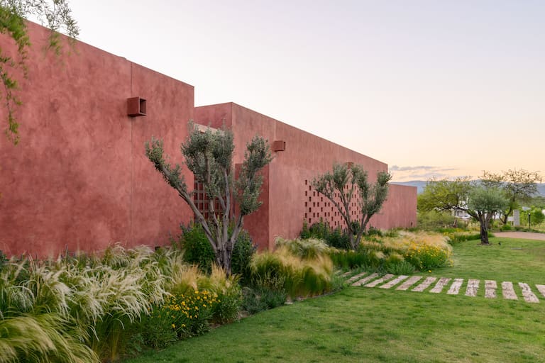 El piso de calcáreo dibuja la geometría rectangular de la piscina alargada para nadar y los senderos delimitan formas circulares de piedra y césped. La única ventana que da al frente se hizo para enmarcar la vista del Chañar.
Fotos: Gonzalo Viramonte