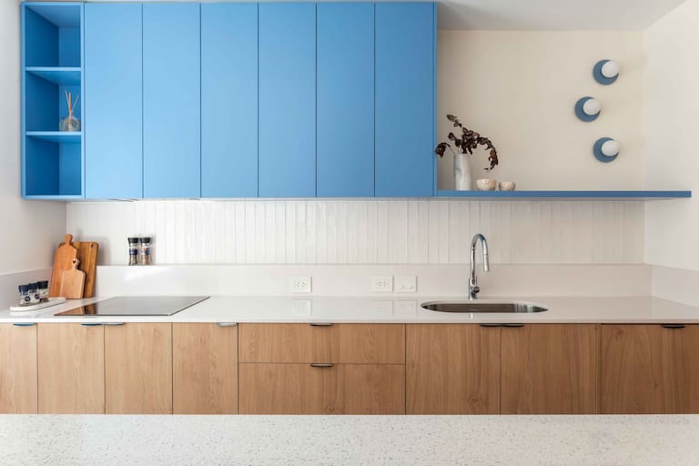 El juego cromático no termina en los muebles y la columna: se amplifica con la iluminación. Las lámparas circulares (DA Iluminación), pintadas a mano para copiar el mismo color de la alacena, acompañan la idea de lo lúdico. Debajo, tiras de luces led y spots garantizan la luz funcional.