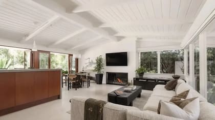 Living de planta abierta con diseño funcional, mobiliario de líneas simples y amplios ventanales corredizos que permiten la integración visual y física con el jardín exterior