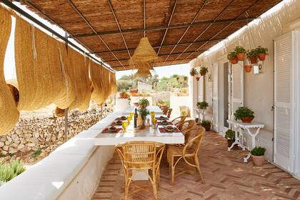 Mesa de obra con tapa revestida en azulejos bajo una pérgola de esparto, como las cortinas.