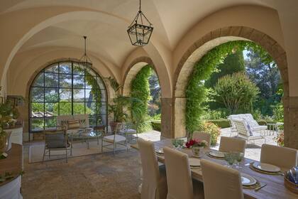 Living y comedor exterior con un patio con techo abovedado y vista a la fuente con nenúfares