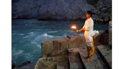 Lokesh Sharma, de 19 años, un sacerdote hindú, realiza oraciones vespertinas a orillas del río Ganges en Devprayag