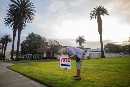 Lorraine Crawford de Huntinghton Beach, California, acomoda un cartel que indica donde se encuentra el centro de votación más cercano