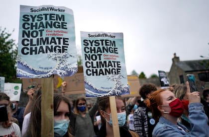 Los activistas climáticos agitan carteles y cantan mientras marchan durante una manifestación que tiene lugar frente a la reunión de líderes del G7