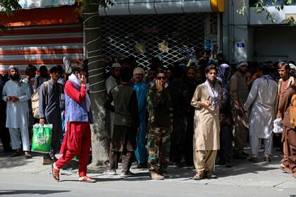 Los afganos esperan en largas filas durante horas para retirar dinero, cerca del Kabul Bank, en Kabul, Afganistán, el domingo 15 de agosto de 2021. Las autoridades dicen que los combatientes talibanes han ingresado a Kabul y buscan la rendición incondicional del gobierno central. (Foto AP / Rahmat Gul)